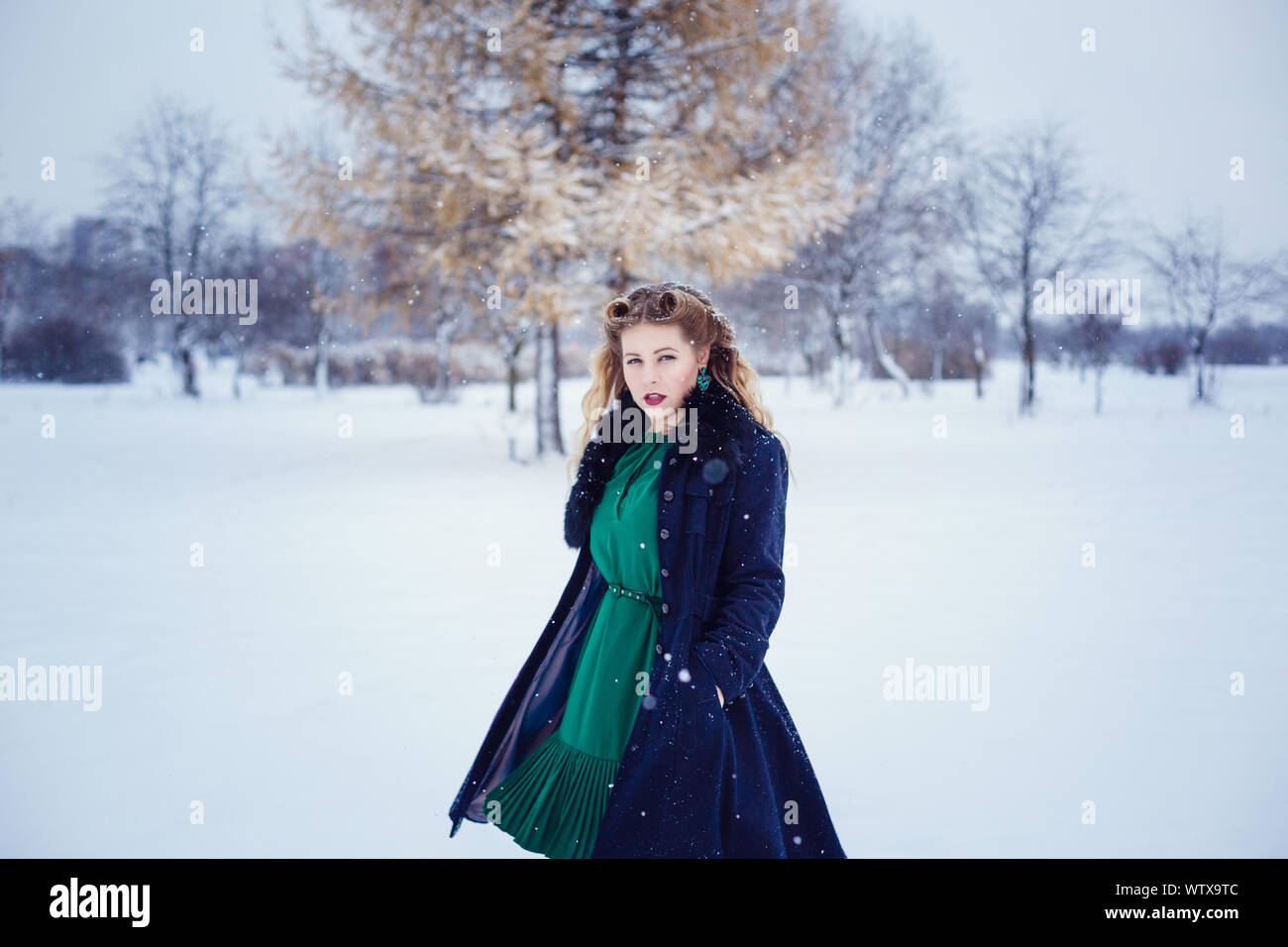 Young beautiful woman walking in a park and breathing fresh winter air ...