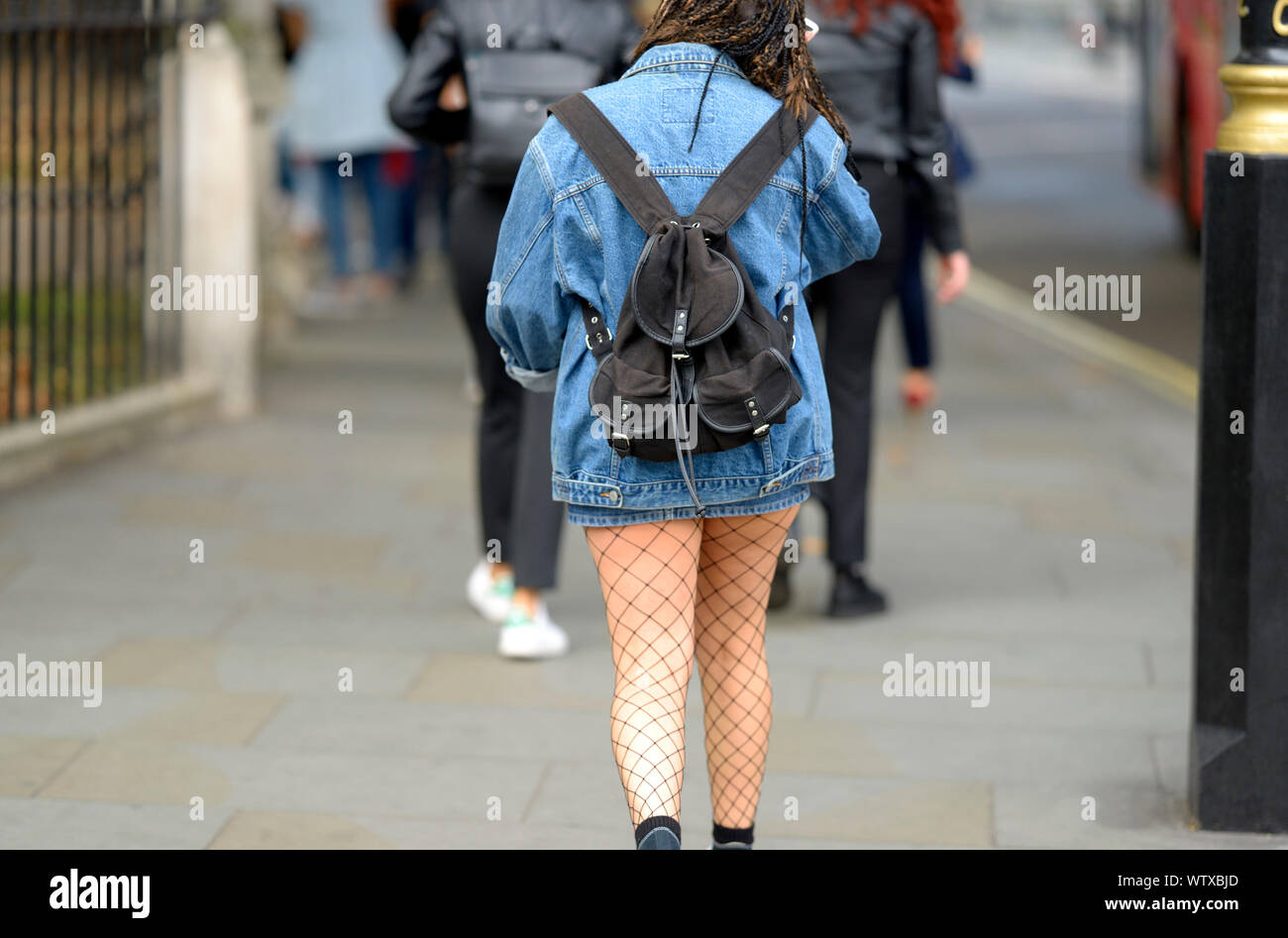 London, England, UK. Young woman with a small rucksach, denim jacket and fishnets Stock Photo