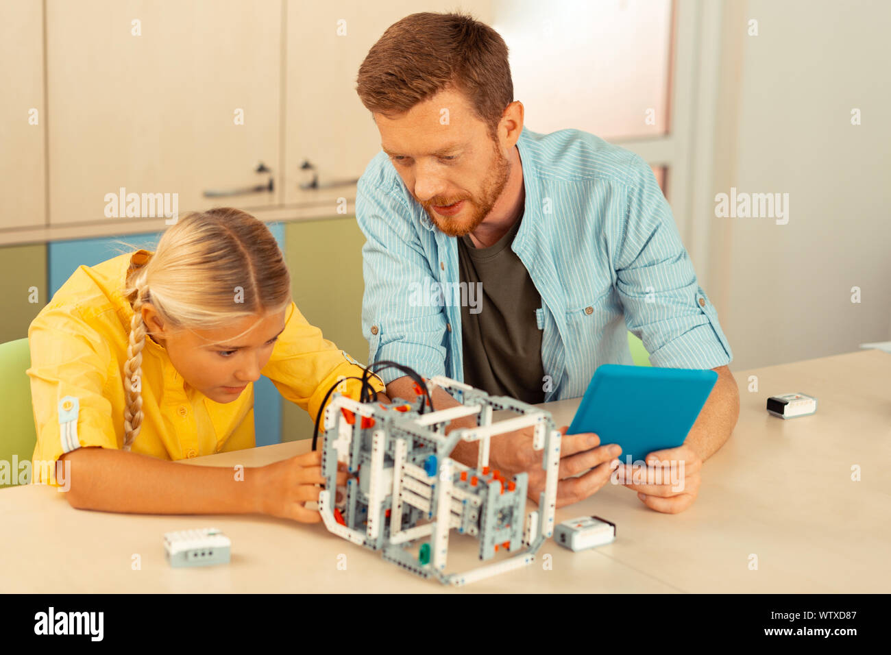 Teacher helping a schoolgirl building a robot Stock Photo - Alamy