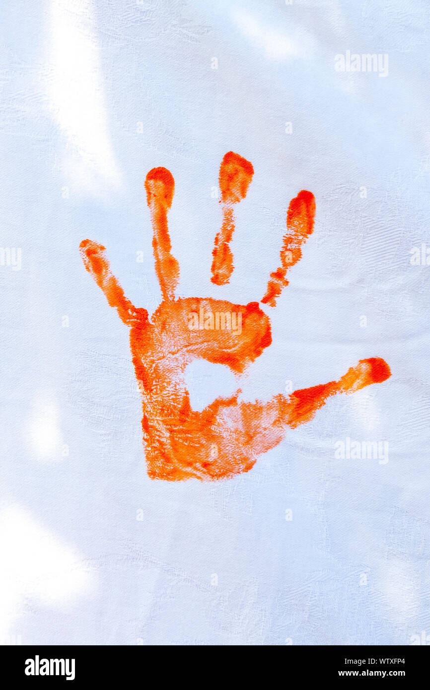 Orange hand paint done by kids on white fabric. Stock Photo