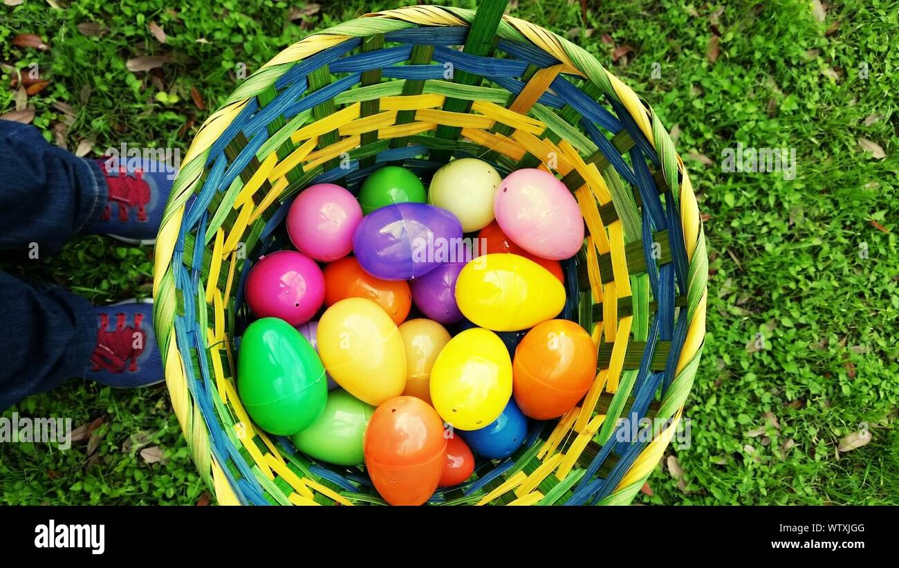 Low Section Of Child Standing By Easter Eggs In Basket On Field Stock Photo