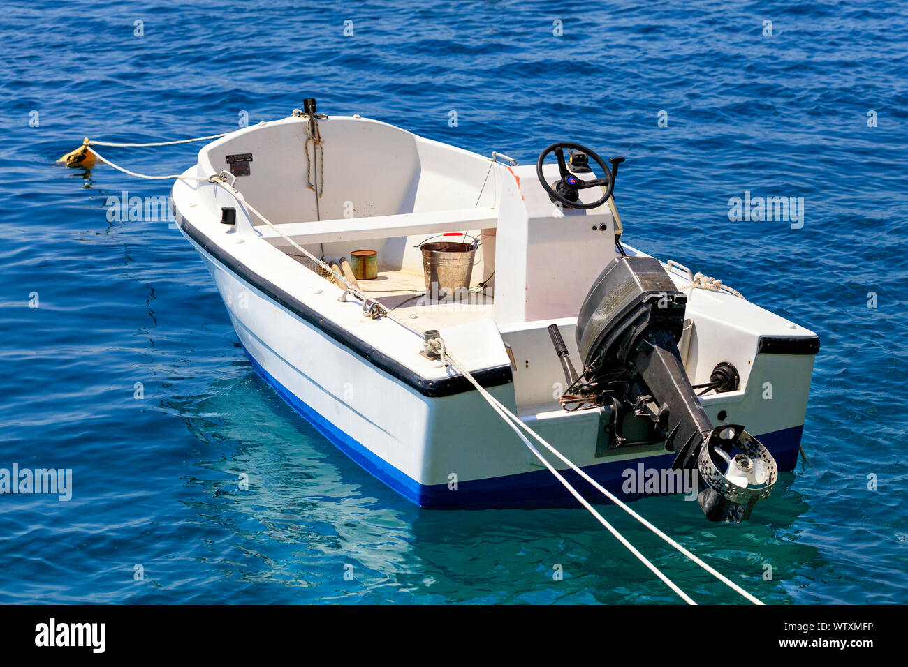 A fishing motor boat is anchored in the clear turquoise waters of