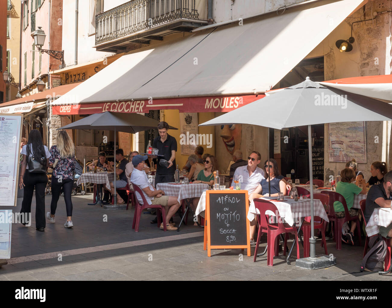 People sitting at the  outdoor street restaurant Le Clocher, in Nice, France, Europe Stock Photo
