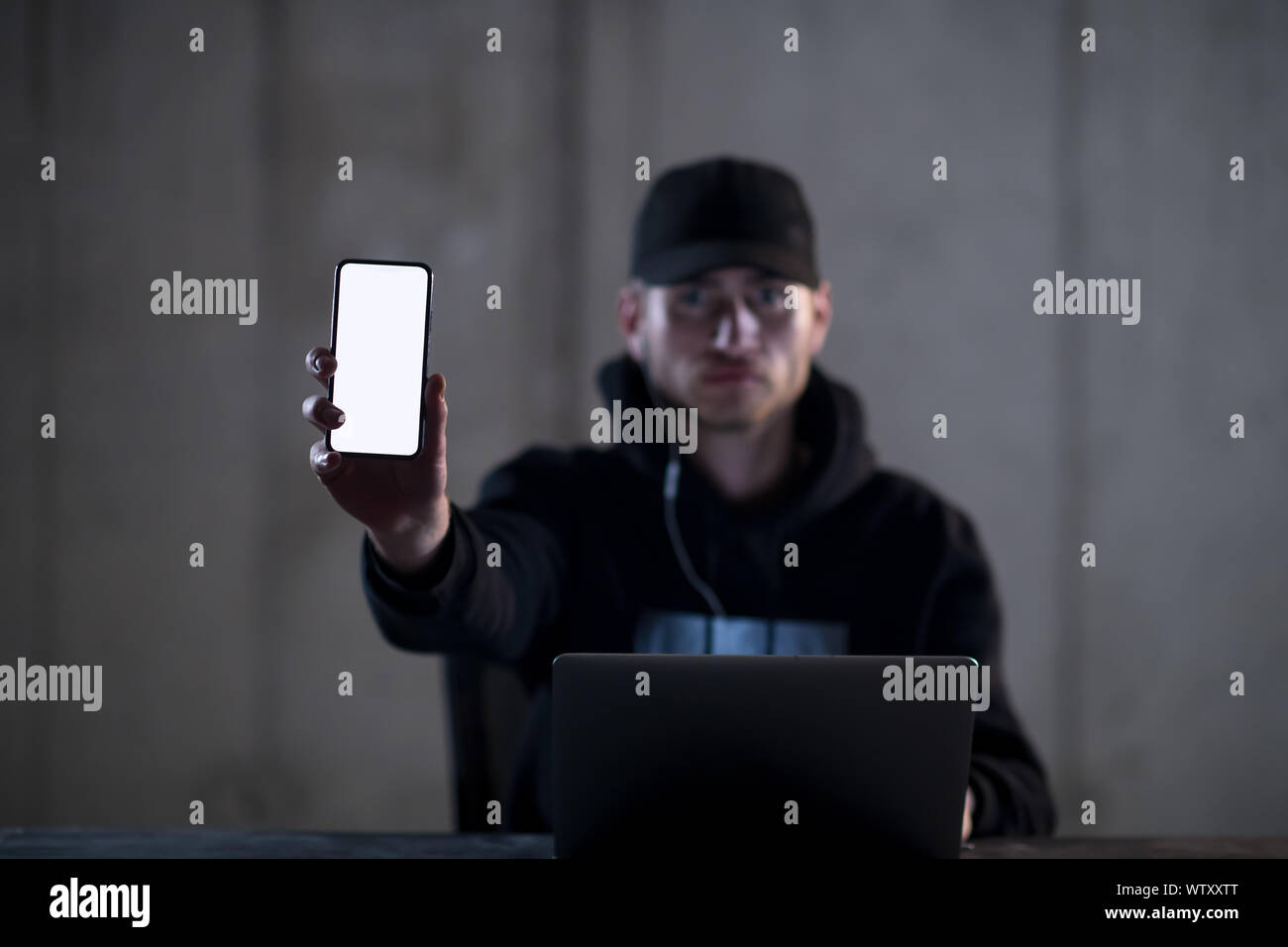 Young talented criminal hacker using laptop computer and showing the ...