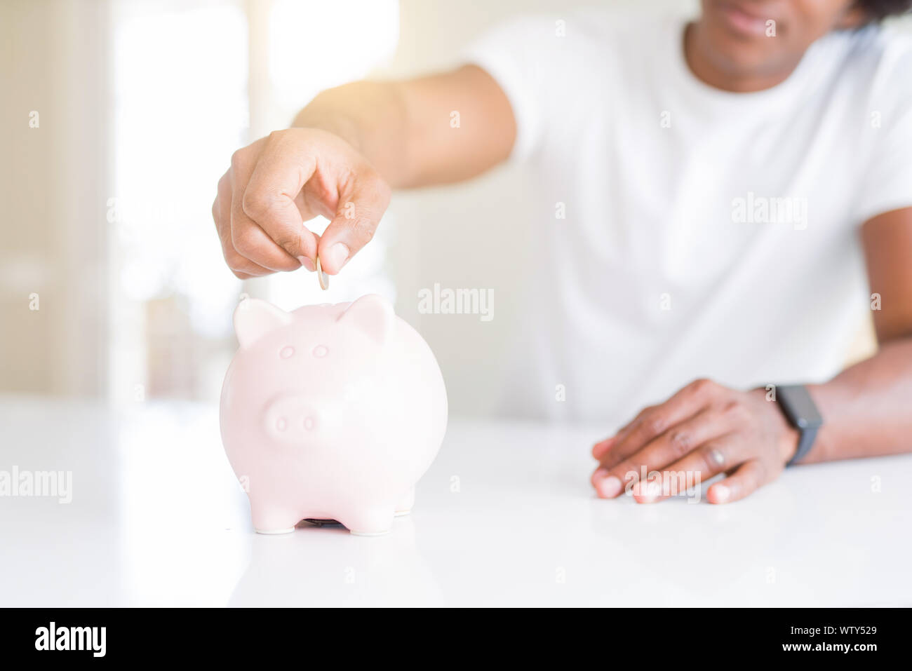 Close up of african american man saving money putting a coin inside ...