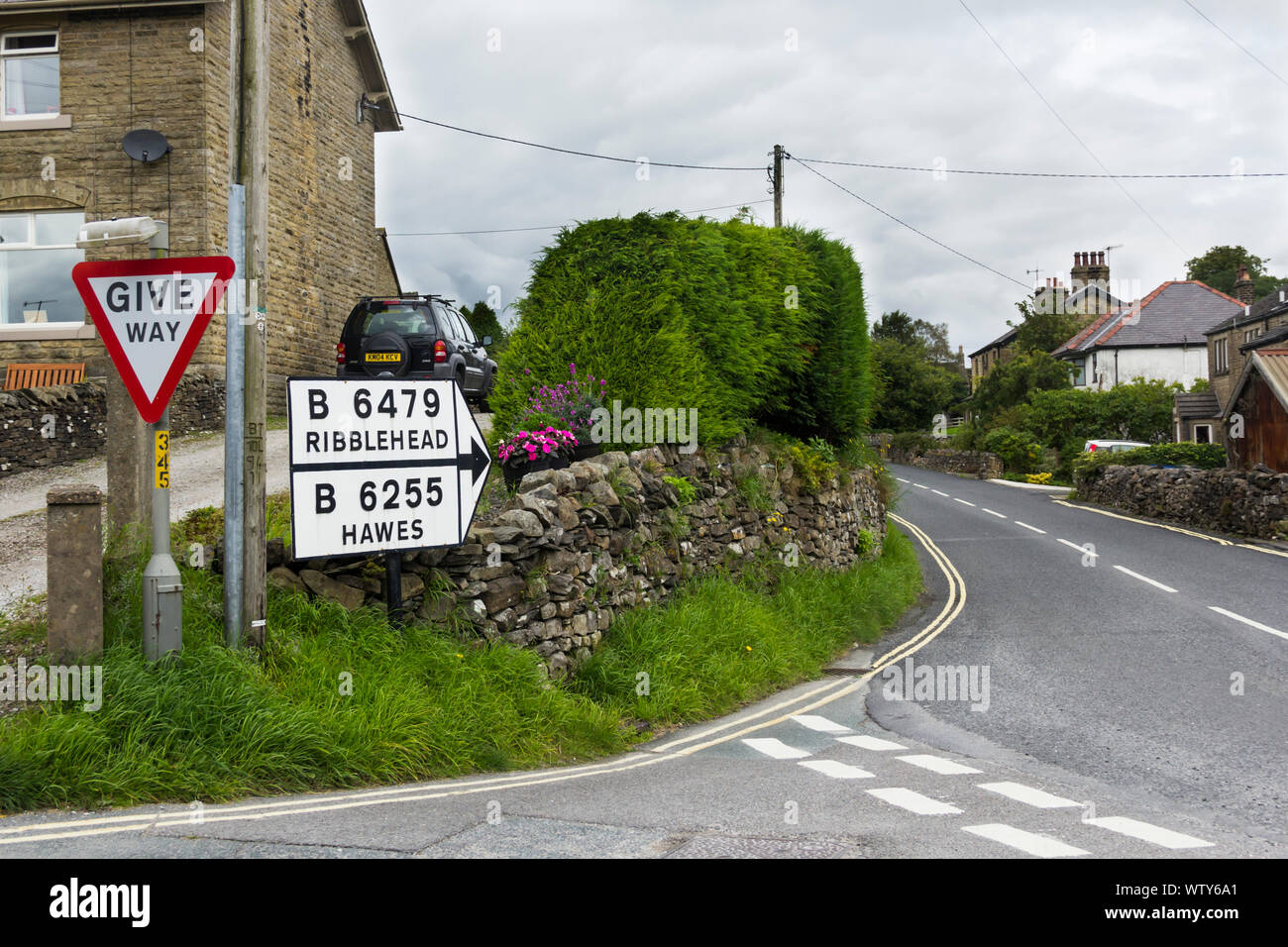 Old style road signs on the country road B6479 at the northern edge of the village of Horton-in-Ribblesdale, North Yorkshire on a dull, cloudy day. Stock Photo