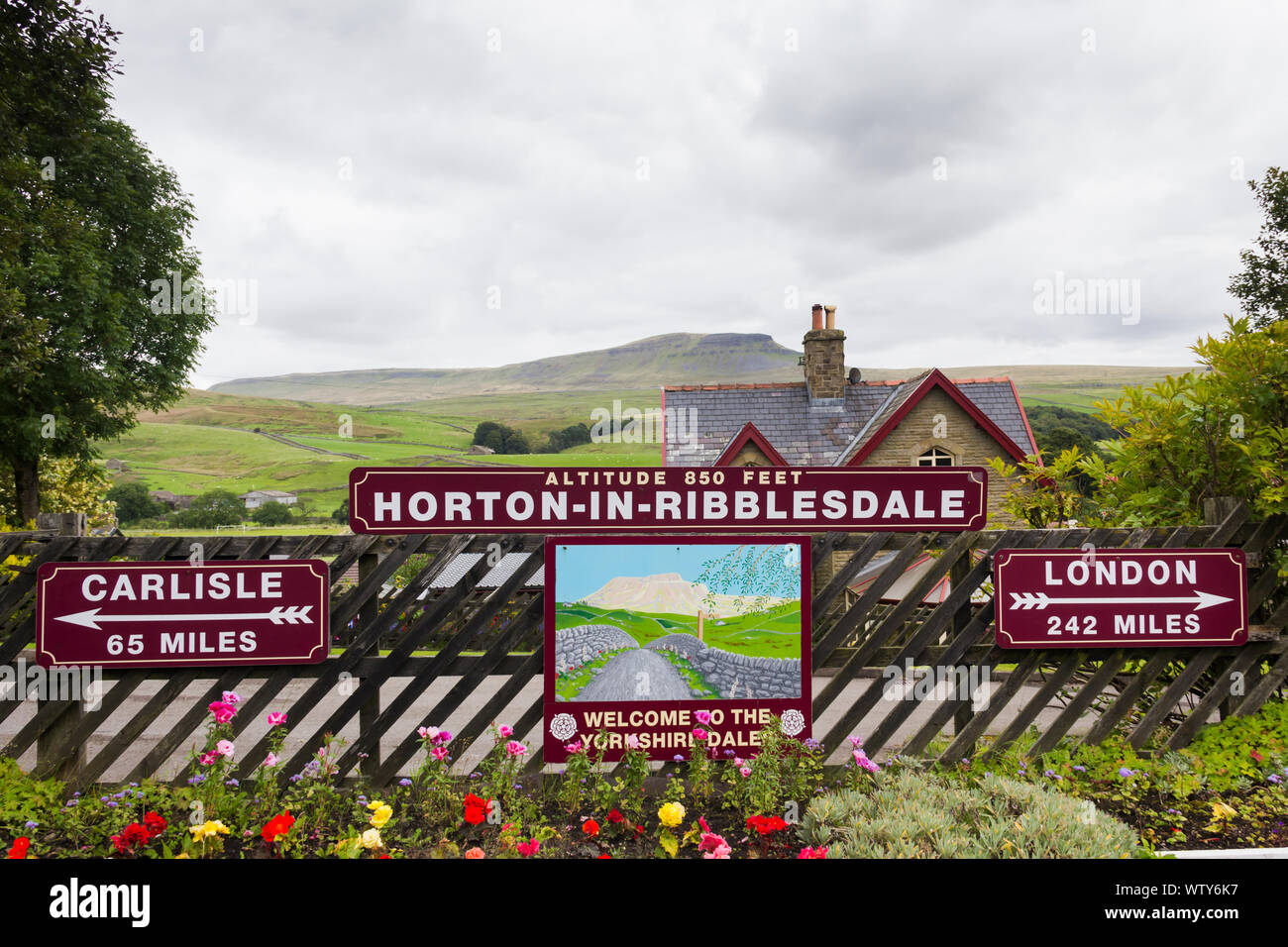 Mileage distance signs for Carlisle and London on the  railway station at Horton-in-Ribblesdale, North Yorkshire overlooked by distant Pen-Y-Ghent Stock Photo