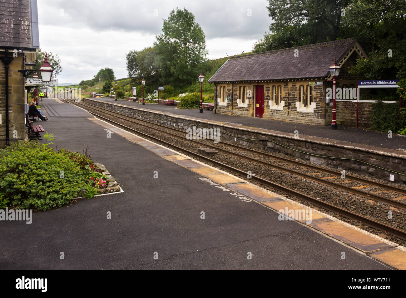The railway station Horton-in-Ribblesdale, North Yorkshire on a dull, cloudy day, with a diesel passenger train approaching northbound in the distance Stock Photo