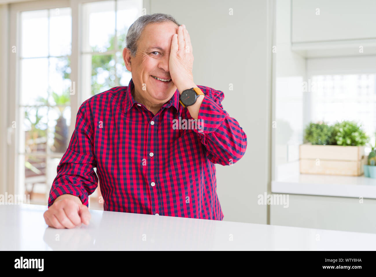 Handsome senior man at home covering one eye with hand with confident ...
