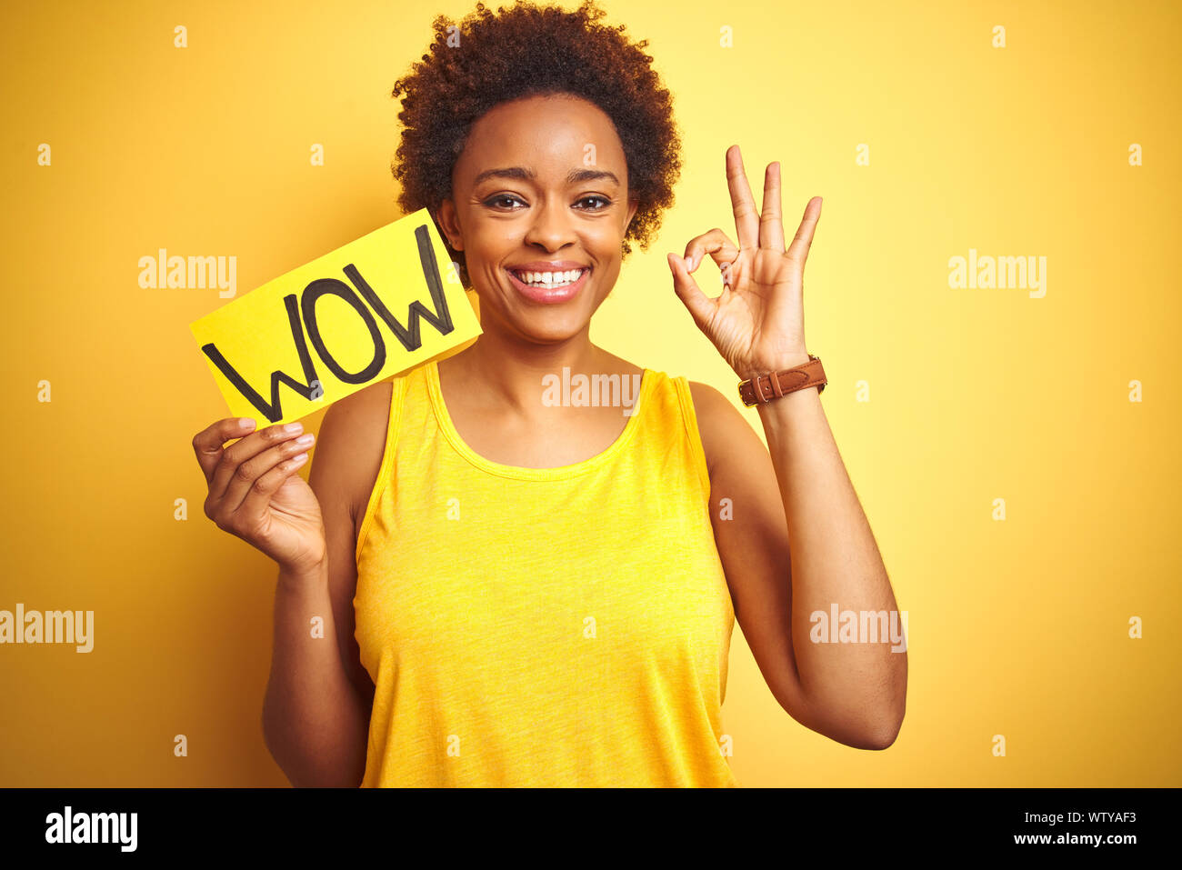 Young african american woman showing wow banner board over yellow ...