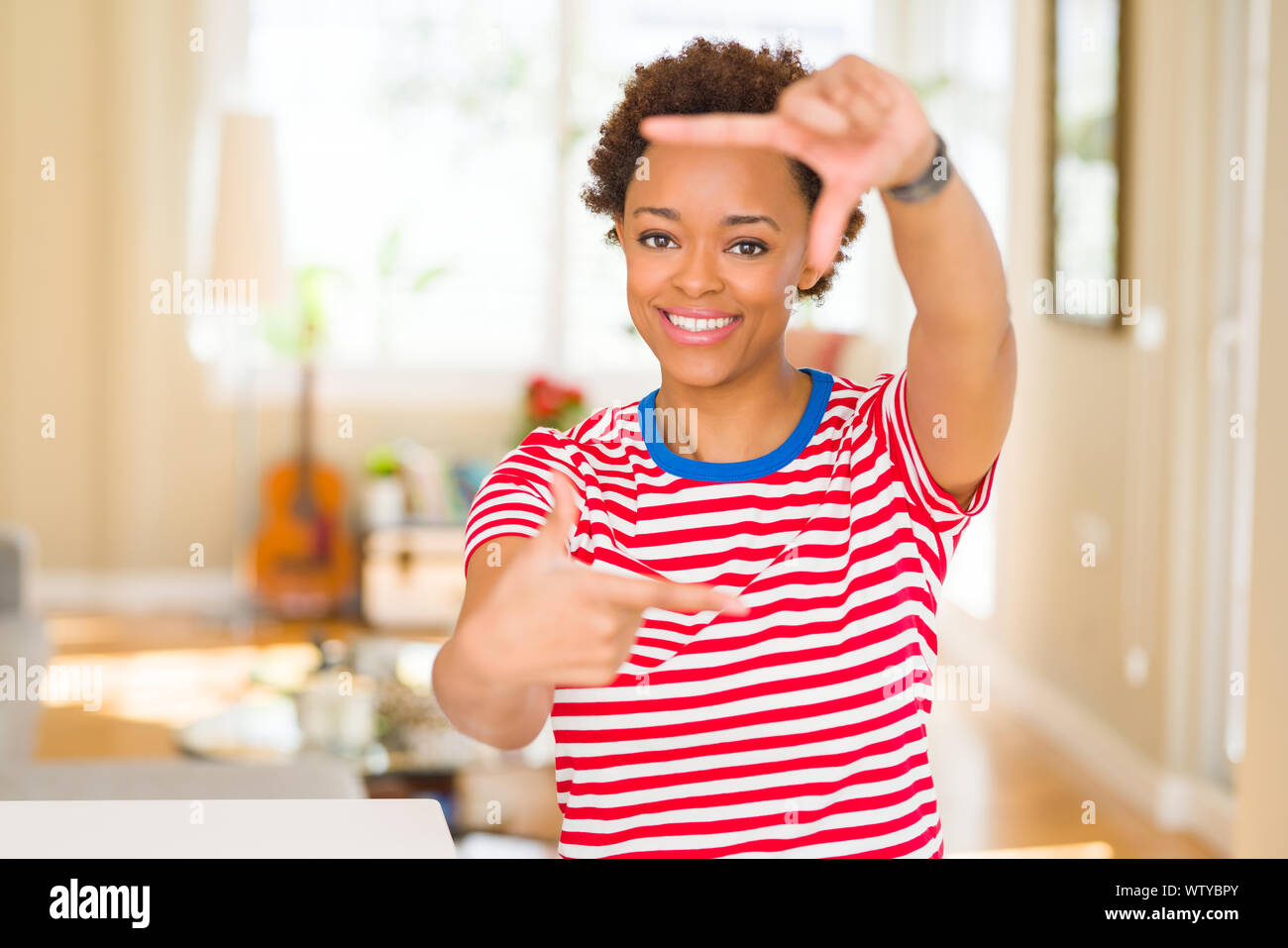 Young beautiful african american woman at home smiling making frame ...