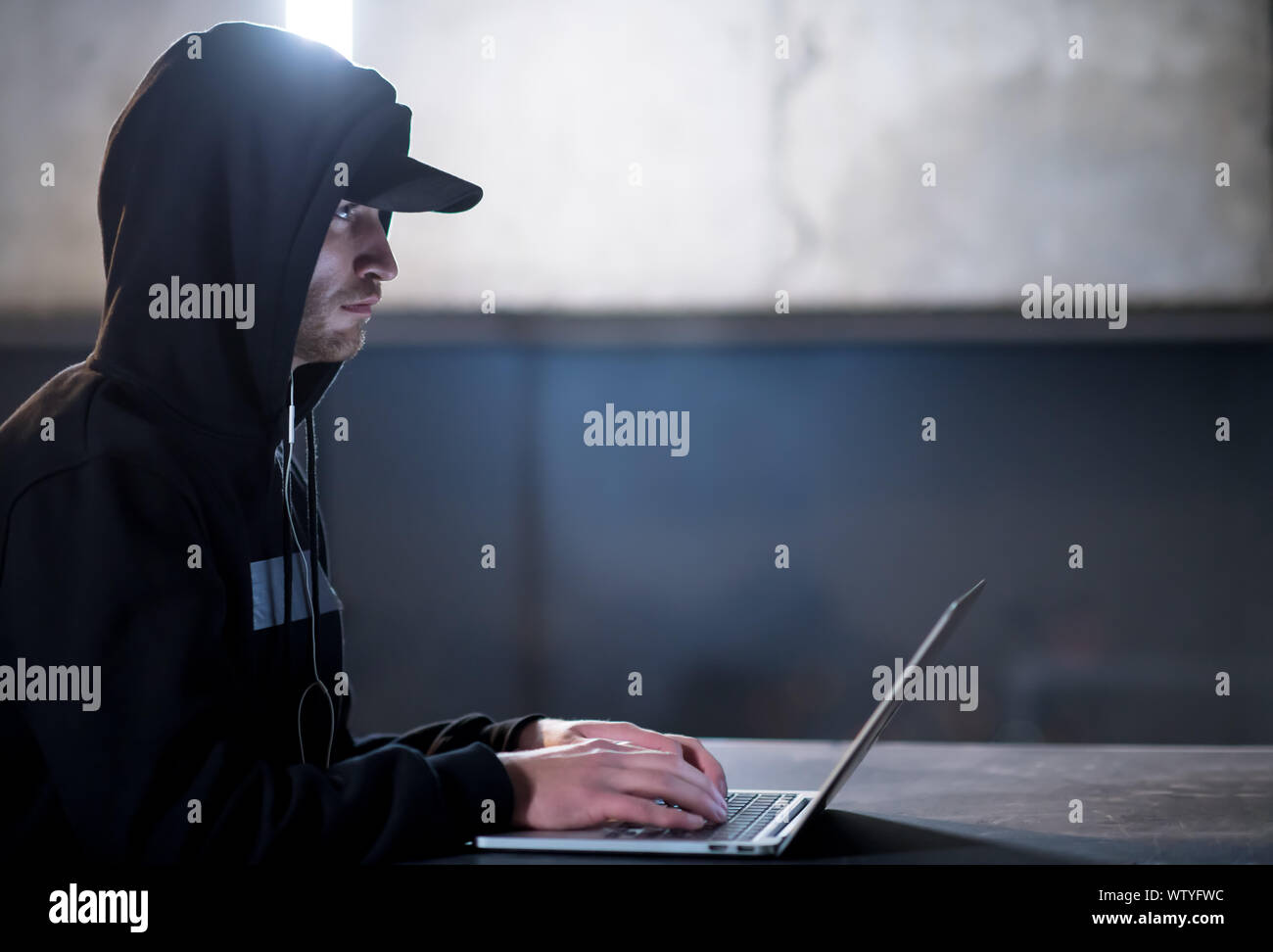 Young talented hacker using laptop computer while working in dark ...