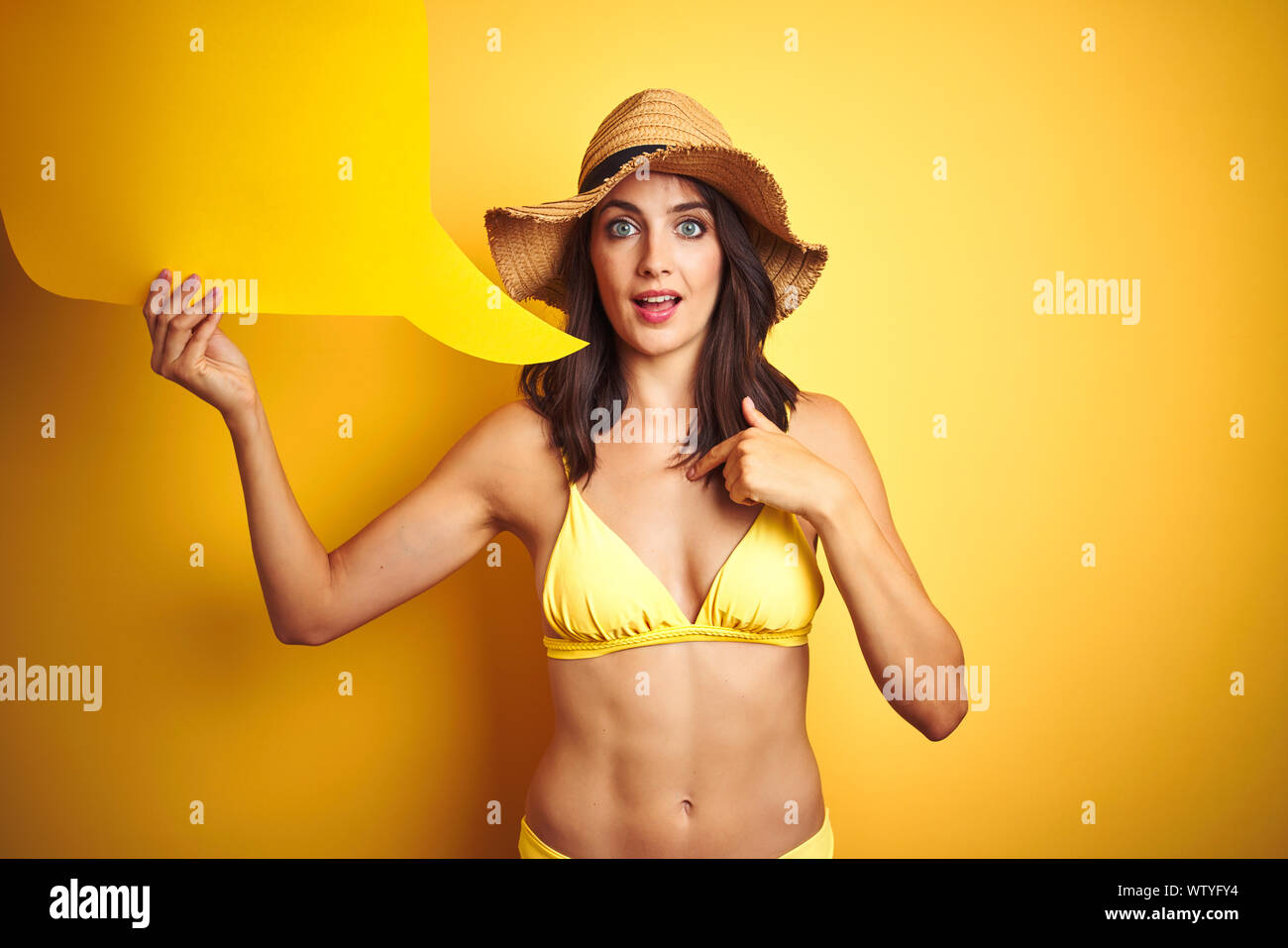 Beautiful woman wearing yellow bikini and holding talking balloon