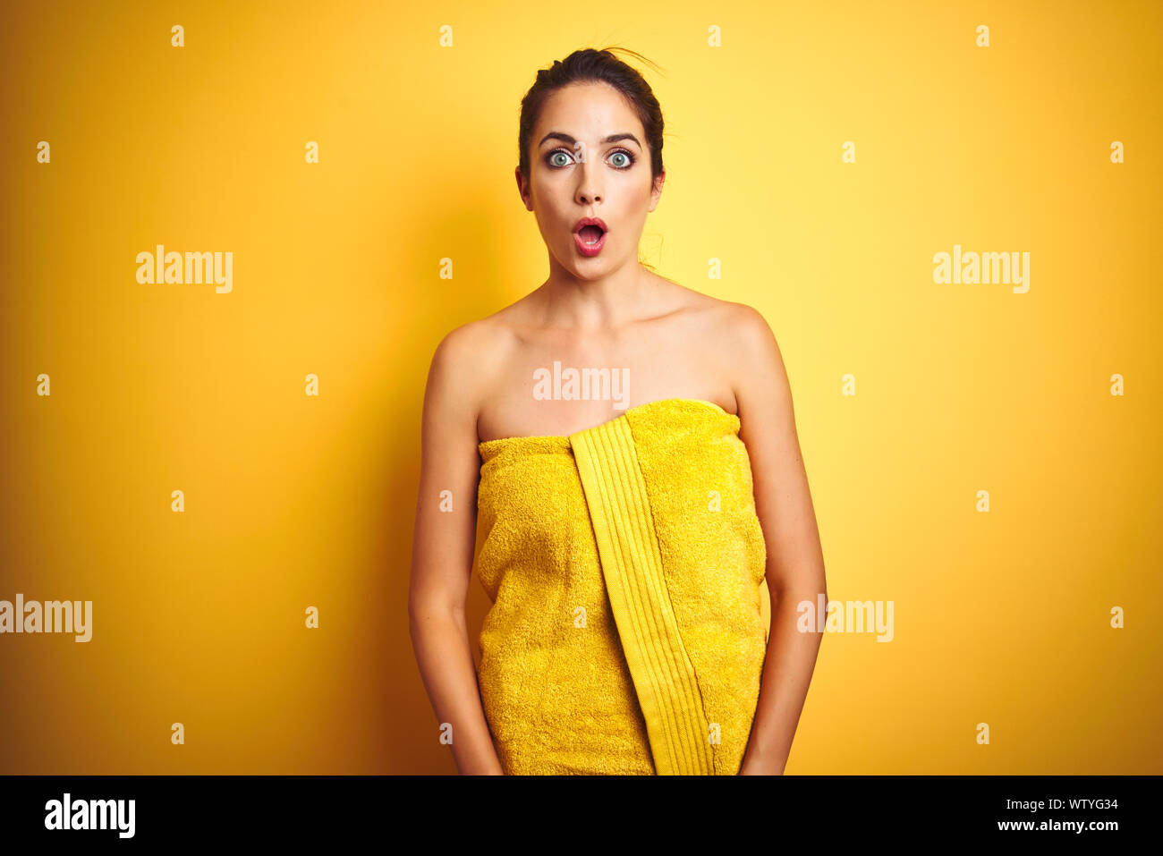 Young beautiful woman wearing towel after shower over yellow isolated