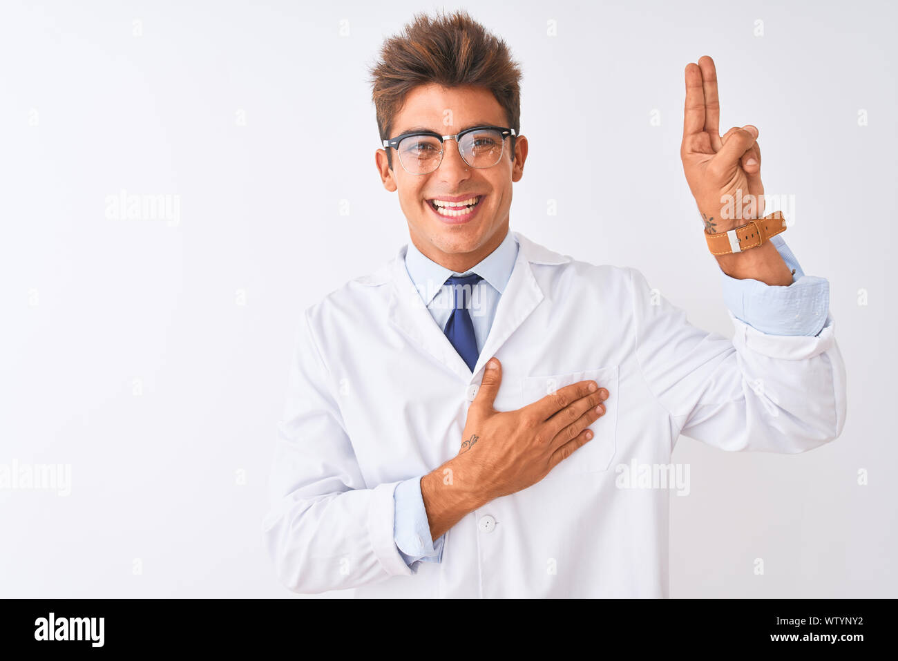 Young handsome sciencist man wearing glasses and coat over isolated white background smiling swearing with hand on chest and fingers up, making a loya Stock Photo