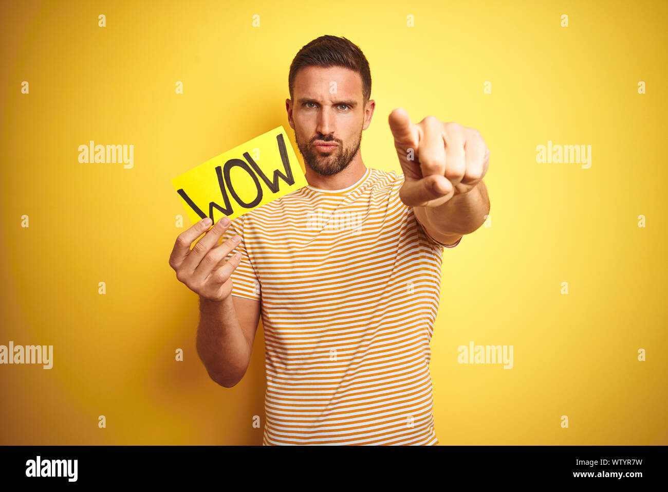 Wow Sign Hand Young man holding wow text banner over yellow isolated background ...