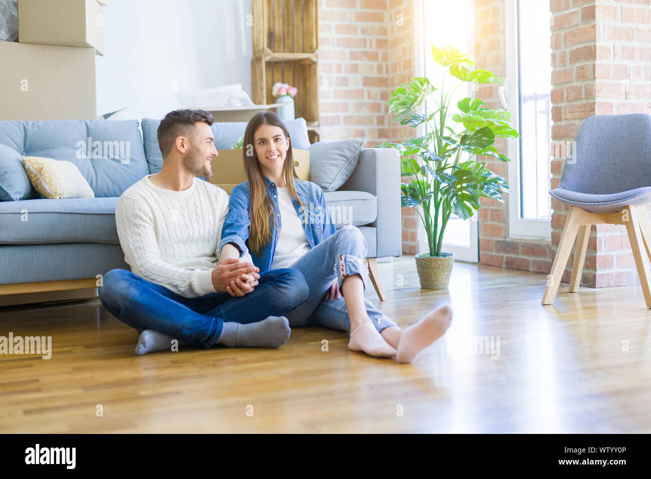 Young beautiful couple sitting on the floor of new apartment, smiling ...