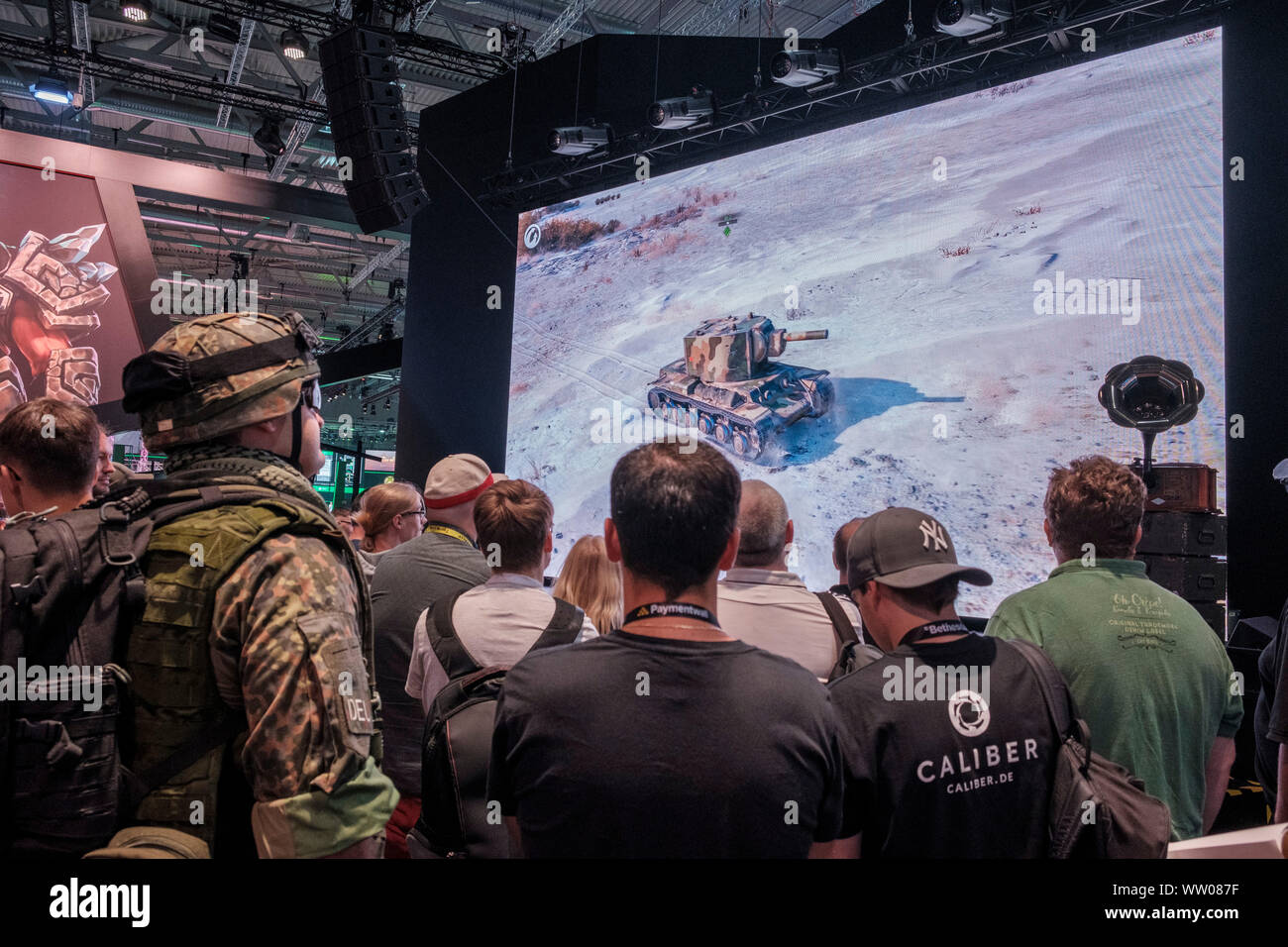 man in military clothing watches tank on screen during presentation of war game  at gamescom , world’s largest trade fair for computer and video games in Cologne, Germany on  August 21, 2019 Stock Photo