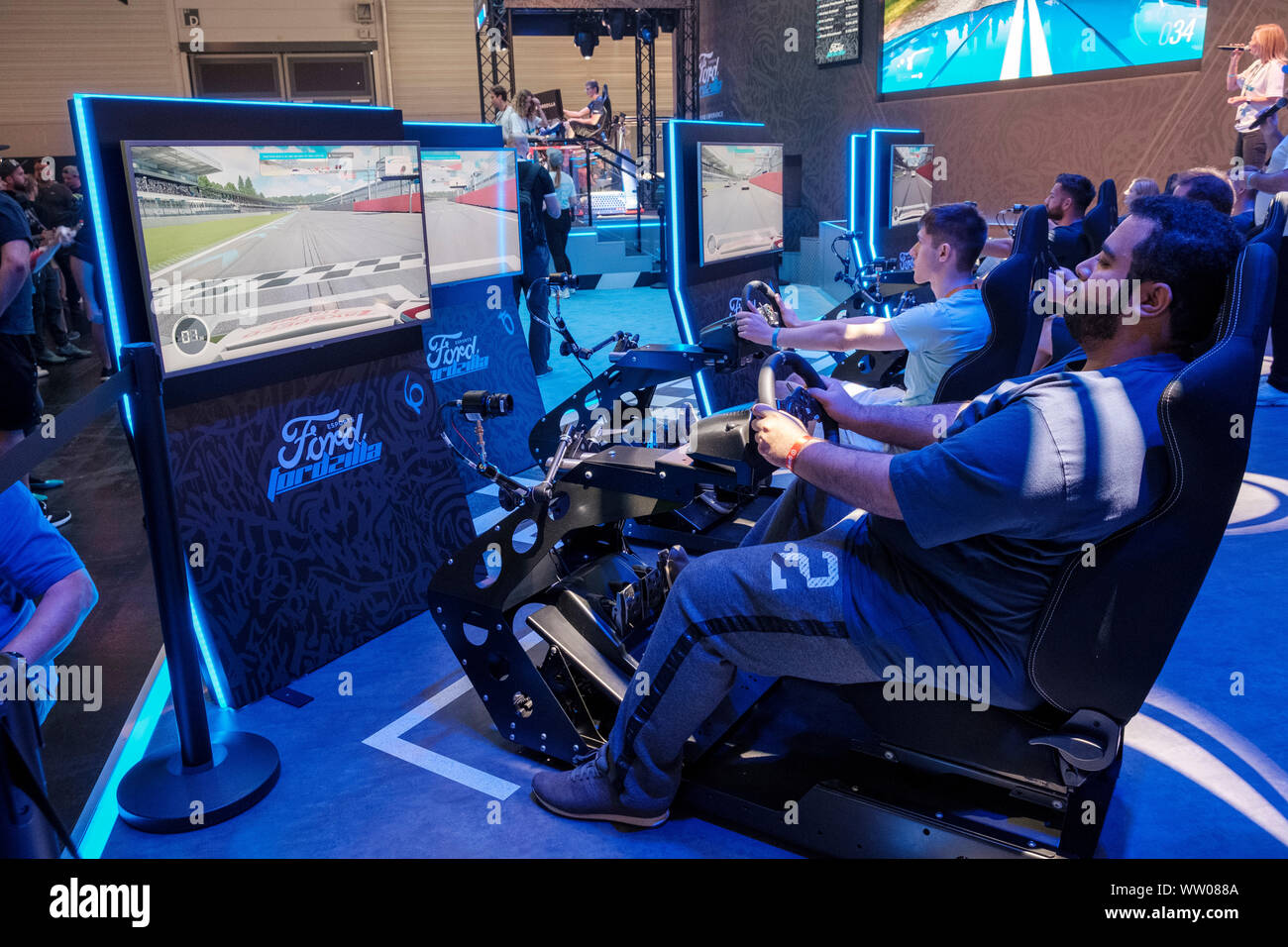 visitors play car racing game on multiple screens  in driving simulator at gamescom , world’s largest trade fair for computer and video games in Cologne, Germany on  August 21, 2019 Stock Photo