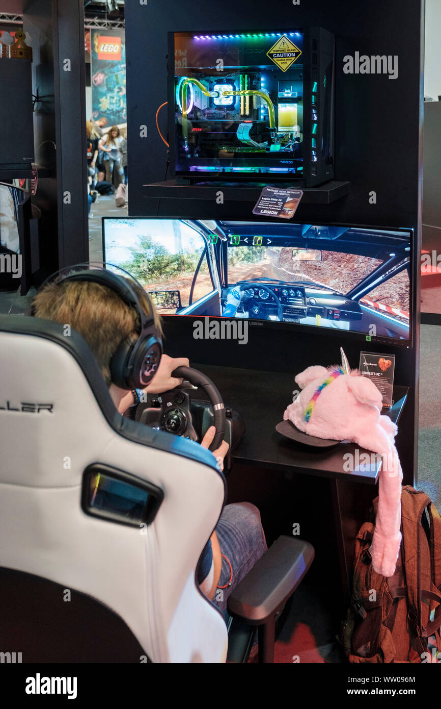 boy plays car racing game on wide screen  in driving simulator at gamescom , world’s largest trade fair for computer and video games in Cologne, Germany on  August 21, 2019 Stock Photo