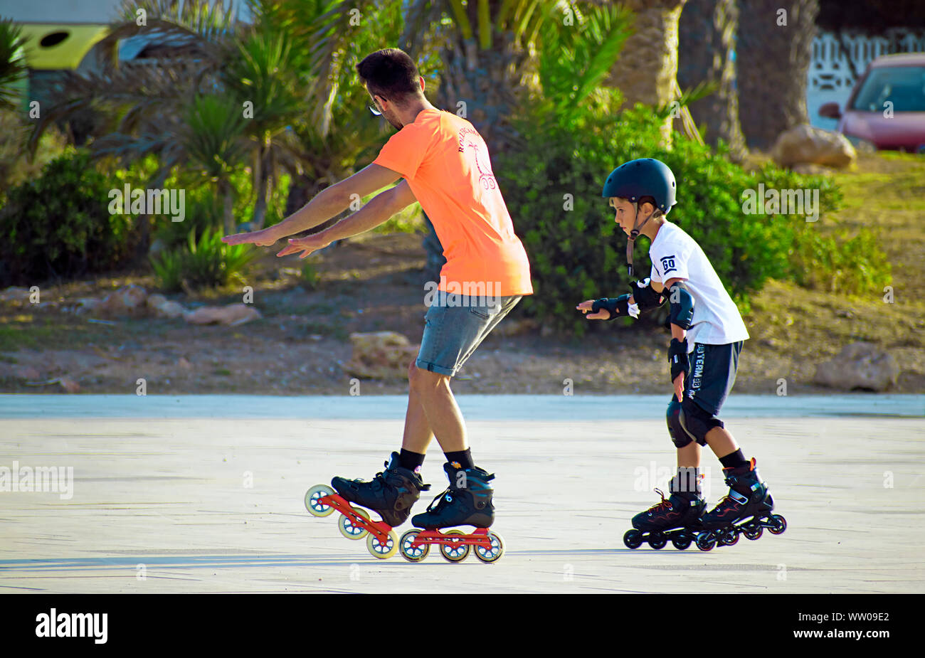 Barcelona, Spain, August 28, 2019: Children learning to skate in line happily at the park during summertime. Rollerblades skating learning initiation. Stock Photo