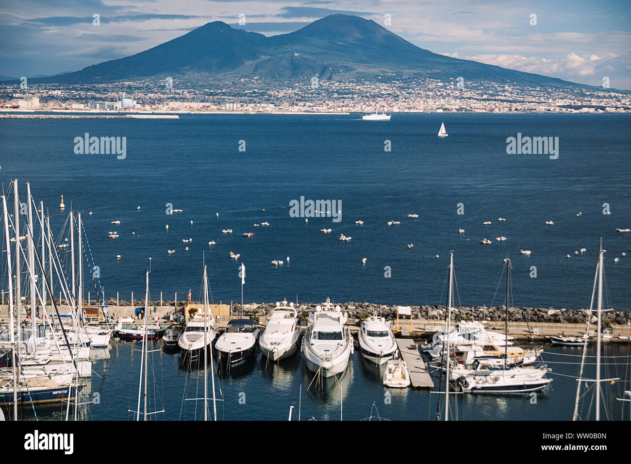Naples cityscape. Volcano Vesuvius in clouds. Volcano and sea landscape. Travel concept. Aerial italian landscape. Italy, Campania. Yachts and sailboat. Stock Photo