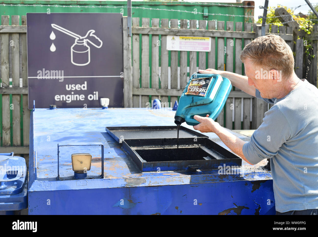 man pouring used engine oil into recycling hopper at council recycling centre uk Stock Photo Alamy