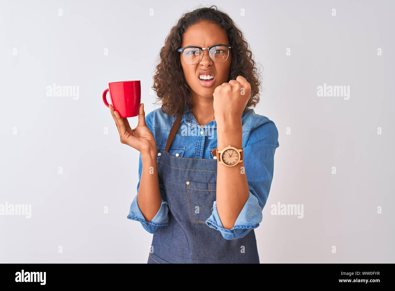 Brazilian barista woman wearing apron drinking cup of coffee over isolated white background annoyed and frustrated shouting with anger, crazy and yell Stock Photo