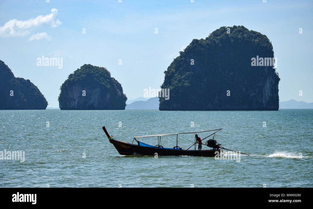 Silhouette of a man driving a long-tail boat in Phang Nga Bay, Thailand. Stock Photo