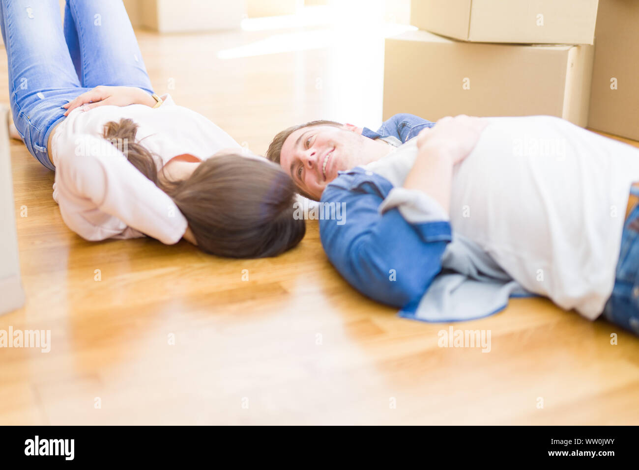 Young beautiful couple relaxing lying on the floor around cardboard
