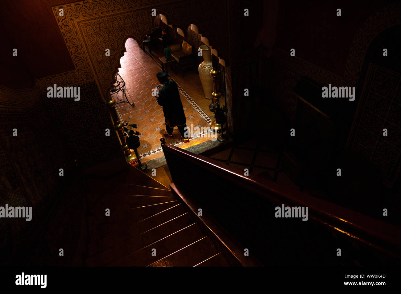 MARRAKESH, MOROCCO - JAN 2019: Arab man with tea in Inner hall of Riad in Marrakesh, Morocco. Rich riad interior Moroccan style arch stairs and mosaic Stock Photo