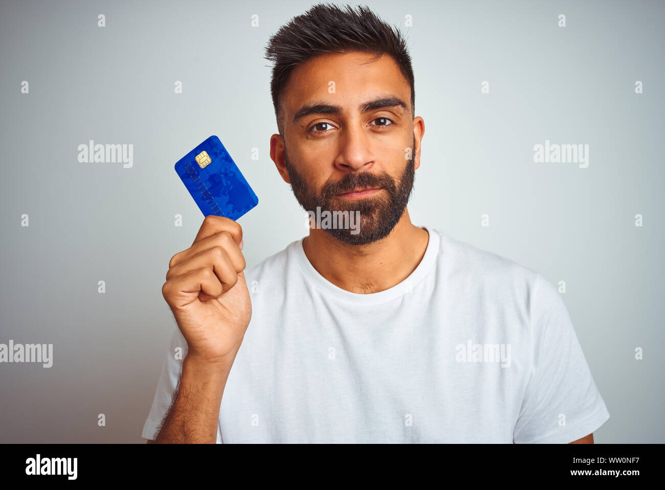 Young indian customer man holding credit card standing over isolated ...