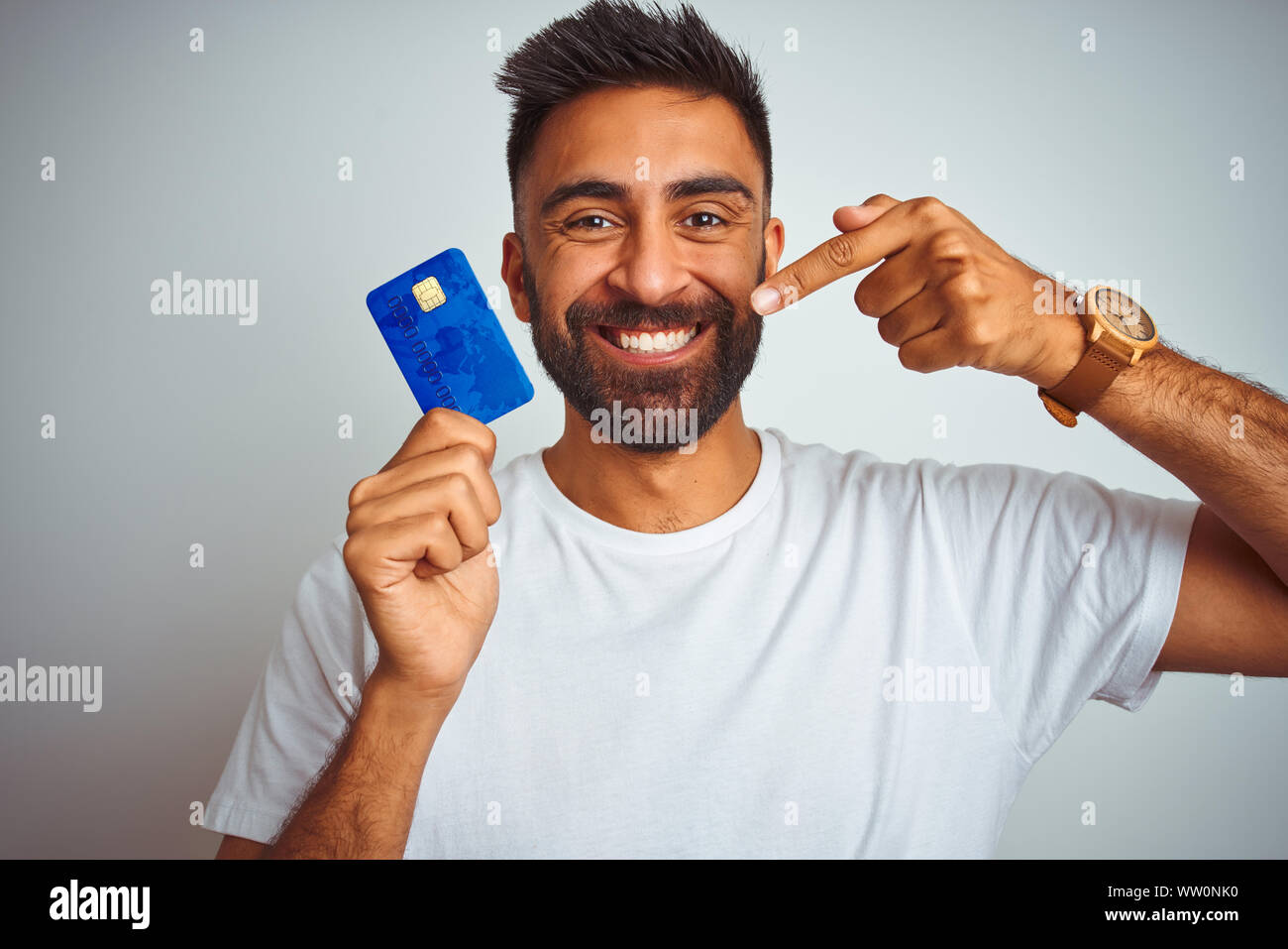 Young indian customer man holding credit card standing over isolated ...