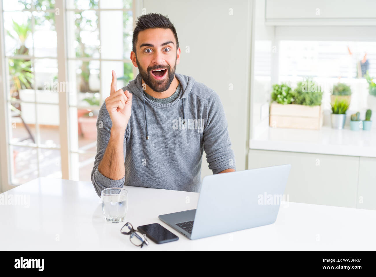 Hispanic Man Using Computer Handsome hispanic man working using computer laptop surprised with an ...