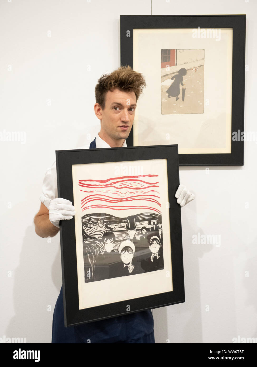 Sotheby’s, London, UK. 12th September 2019. The complete, multi-artist album Les Peintres-Graveurs will be offered at auction in London on Sept 17th, estimate £500,000 - £1,000,000. Initially produced in an edition of 100, its appearance at Sotheby’s London will mark the first time the complete portfolio has been exhibited as a whole for over a century,with all 22 prints by artists including Munch, Bonnard, Vuillard, Redon and Renoir. Image Sotheby’s art handler holds Edvard Munch’s Angst (or Le Soir), a work from the collection. Credit: Malcolm Park/Alamy Live News. Stock Photo