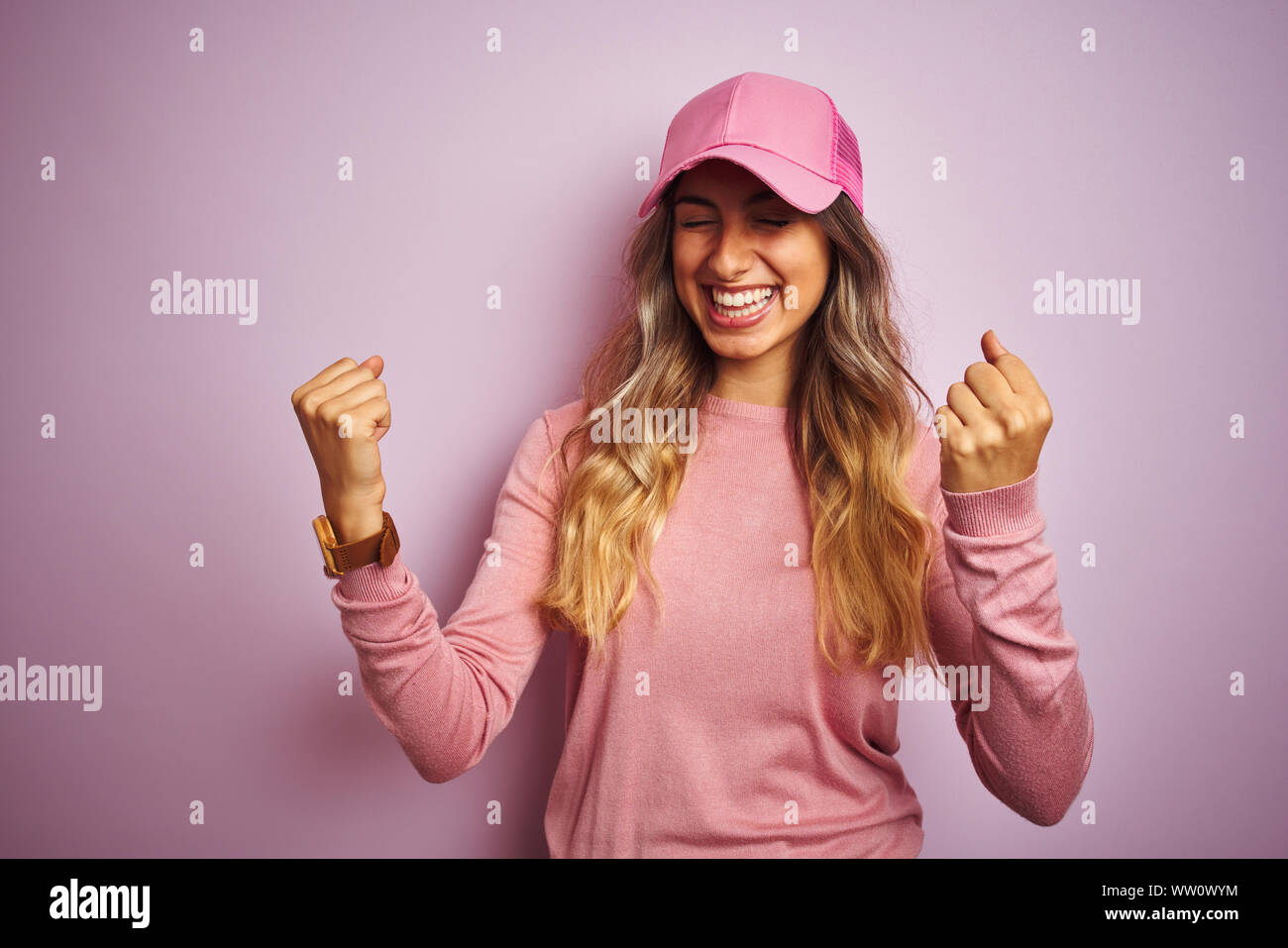 Young beautiful woman wearing cap over pink isolated background very happy and excited doing winner gesture with arms raised, smiling and screaming fo Stock Photo