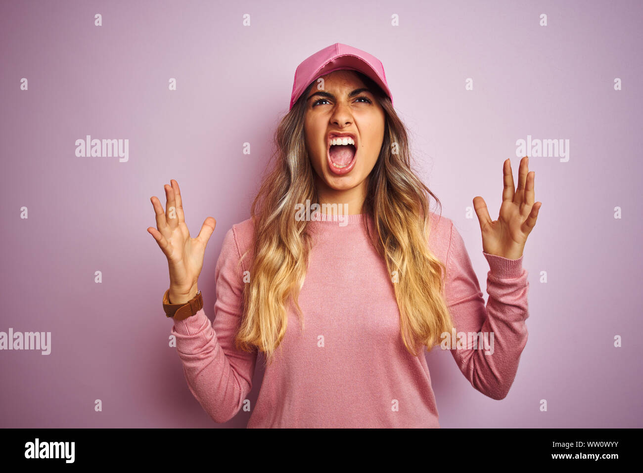 Young beautiful woman wearing cap over pink isolated background crazy and mad shouting and yelling with aggressive expression and arms raised. Frustra Stock Photo