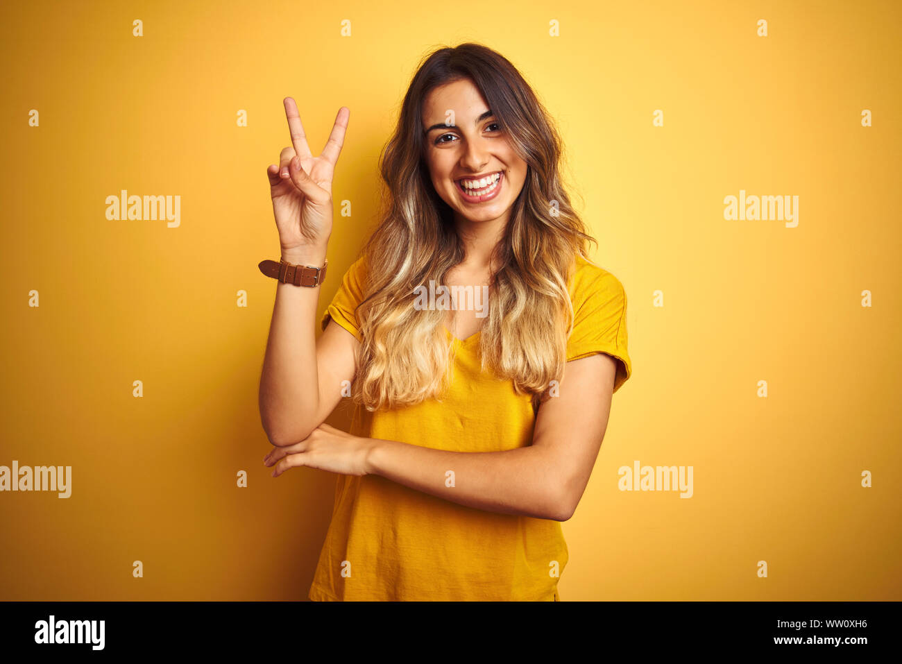 Young beautiful woman wearing t-shirt over yellow isolated background ...