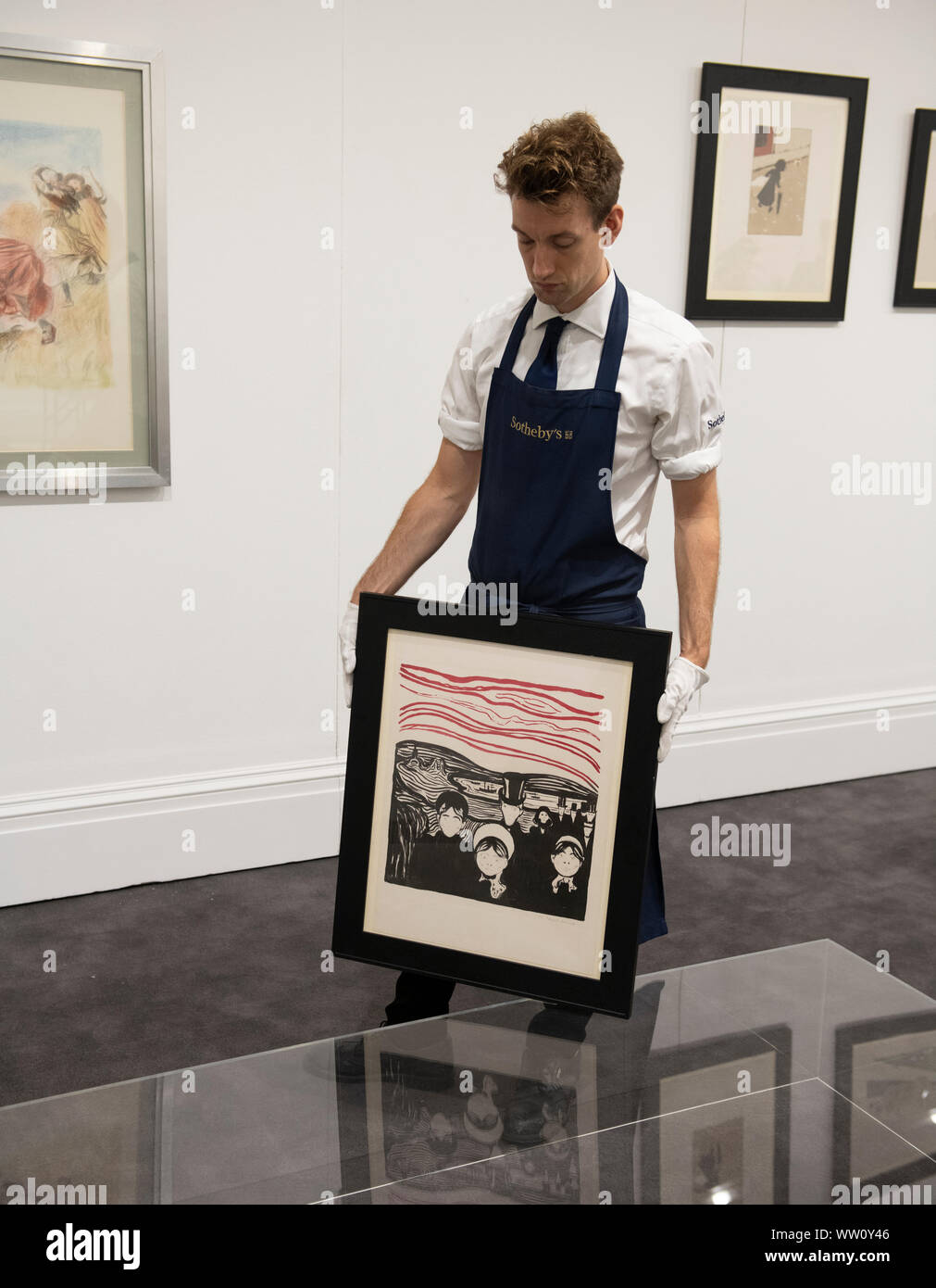 Sotheby’s, London, UK. 12th September 2019. The complete, multi-artist album Les Peintres-Graveurs will be offered at auction in London on Sept 17th, estimate £500,000 - £1,000,000. Initially produced in an edition of 100, its appearance at Sotheby’s London will mark the first time the complete portfolio has been exhibited as a whole for over a century,with all 22 prints by artists including Munch, Bonnard, Vuillard, Redon and Renoir. Image Sotheby’s art handler holds Edvard Munch’s Angst (or Le Soir), a work from the collection. Credit: Malcolm Park/Alamy Live News. Stock Photo