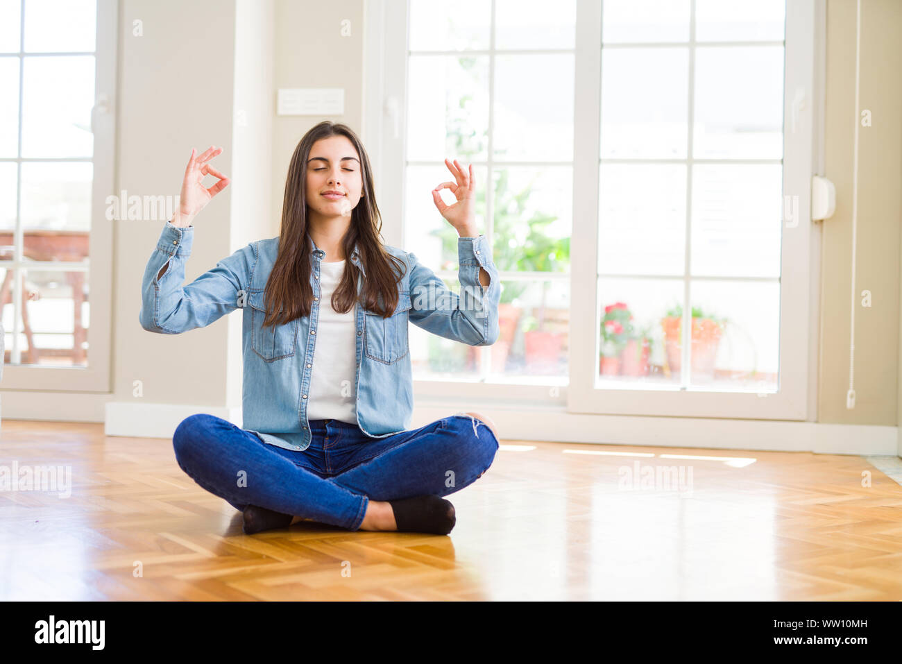 Beautiful young woman sitting on the floor at home relax and smiling ...