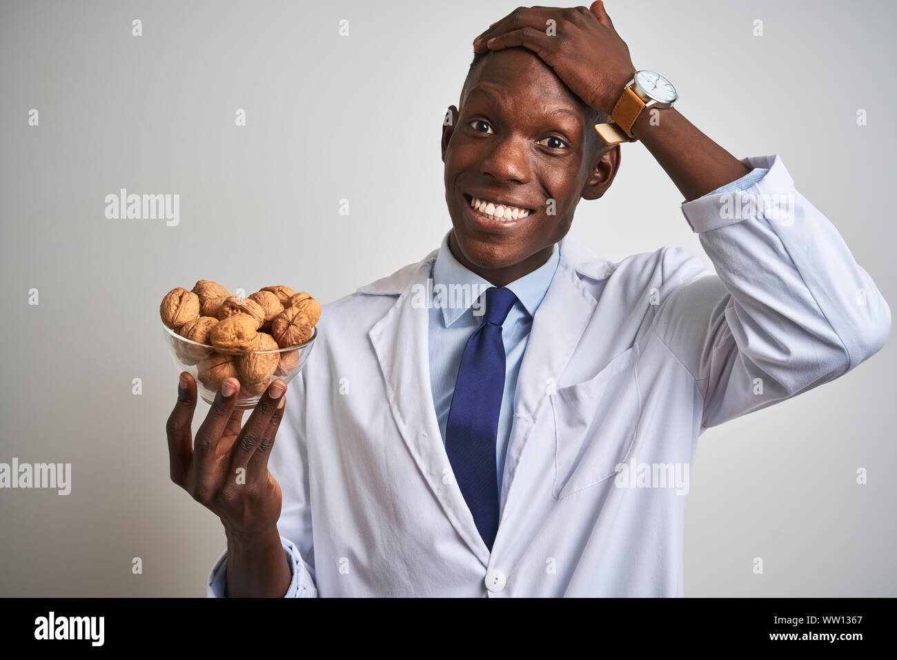 African american doctor man holding bowl with walnuts standing over