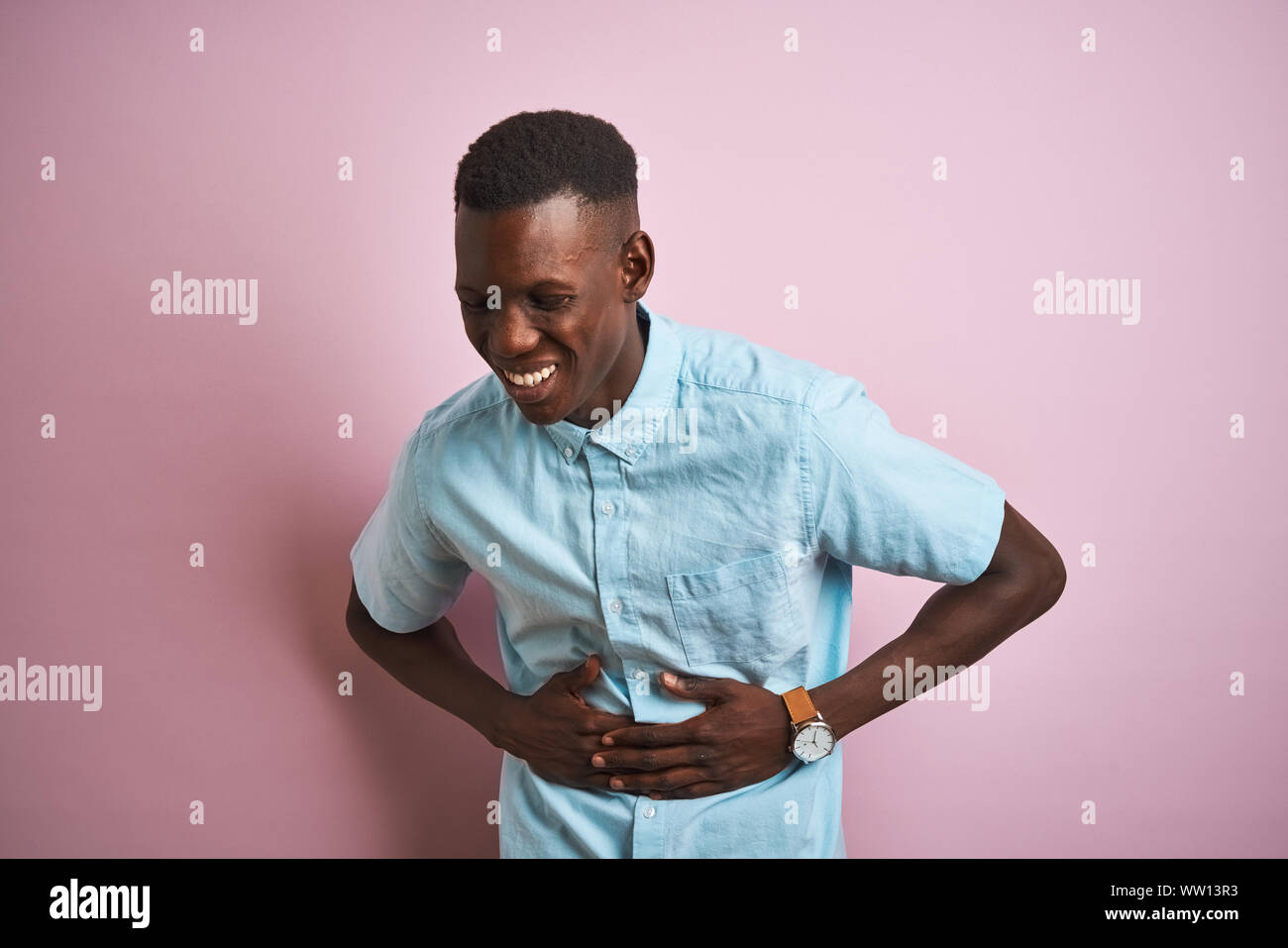 African american man wearing blue casual shirt standing over isolated pink background with hand on stomach because indigestion, painful illness feelin Stock Photo