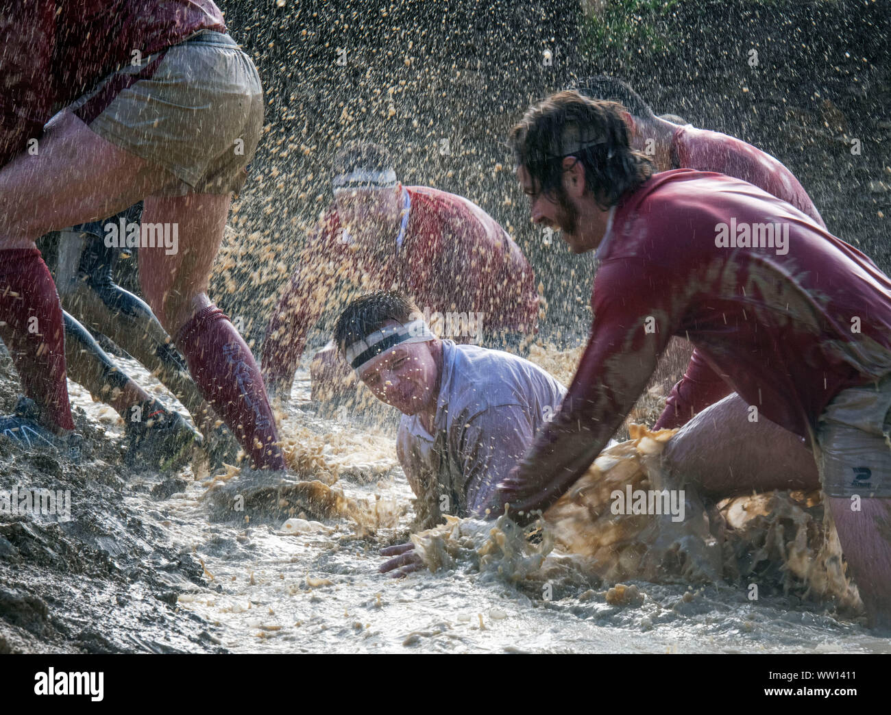 Competitors dressed as England and Wales rugby players on the ‘Mud Mile’ at the Tough Mudder endurance event in Badminton Park, Gloucestershire UK Stock Photo
