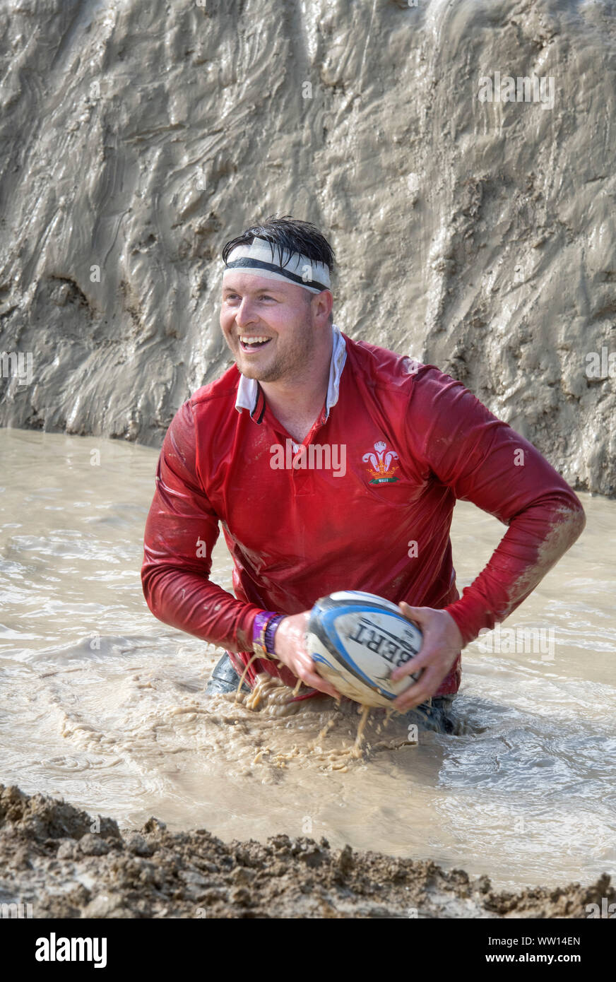 A competitor dressed as a Wales rugby player on the ‘Mud Mile’ at the Tough Mudder endurance event in Badminton Park, Gloucestershire UK Stock Photo