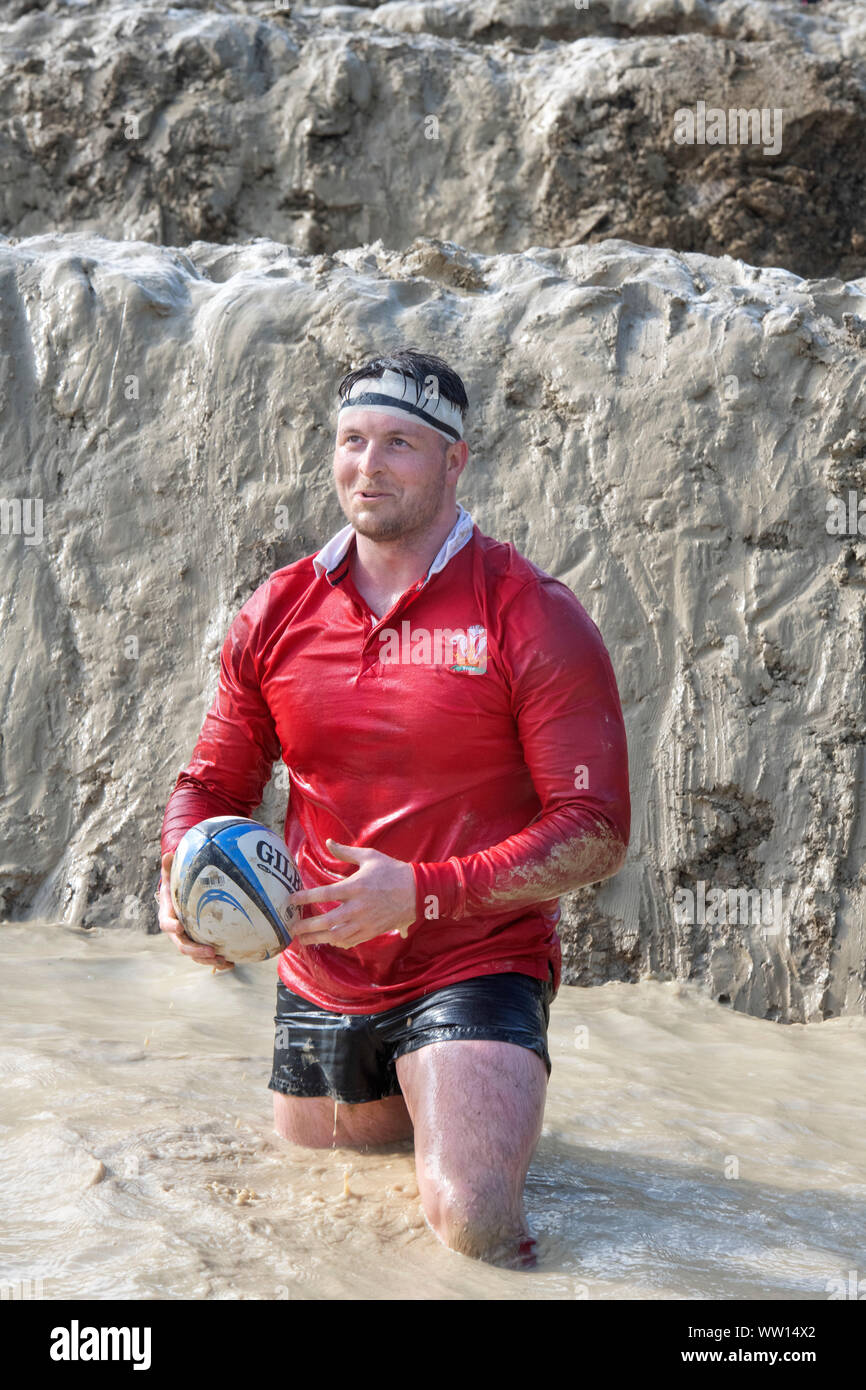 A competitor dressed as a Wales rugby player on the ‘Mud Mile’ at the Tough Mudder endurance event in Badminton Park, Gloucestershire UK Stock Photo