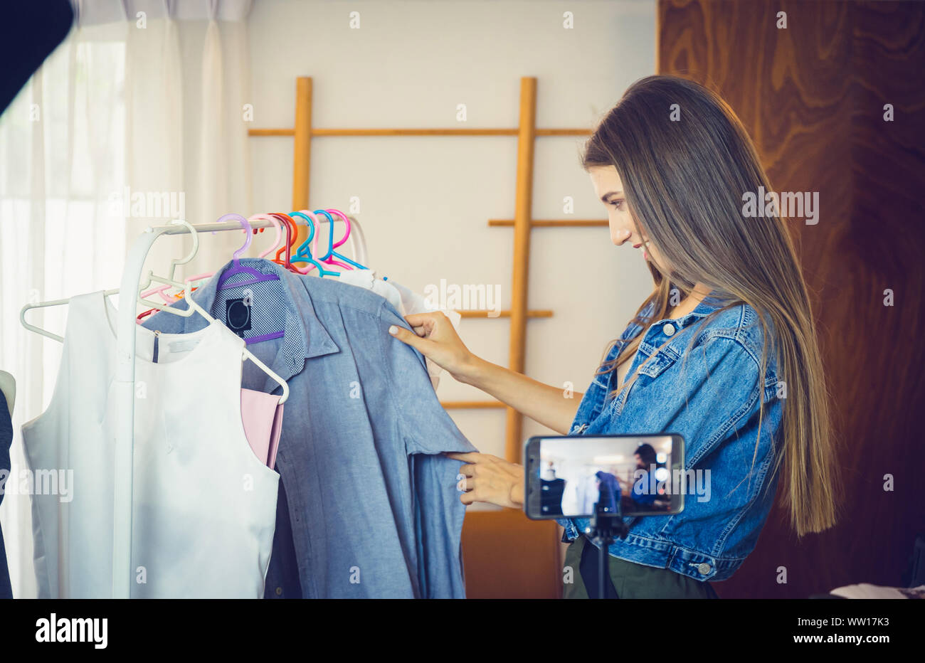 Young girl selling clothes online by live streaming from mobile phone. Stock Photo