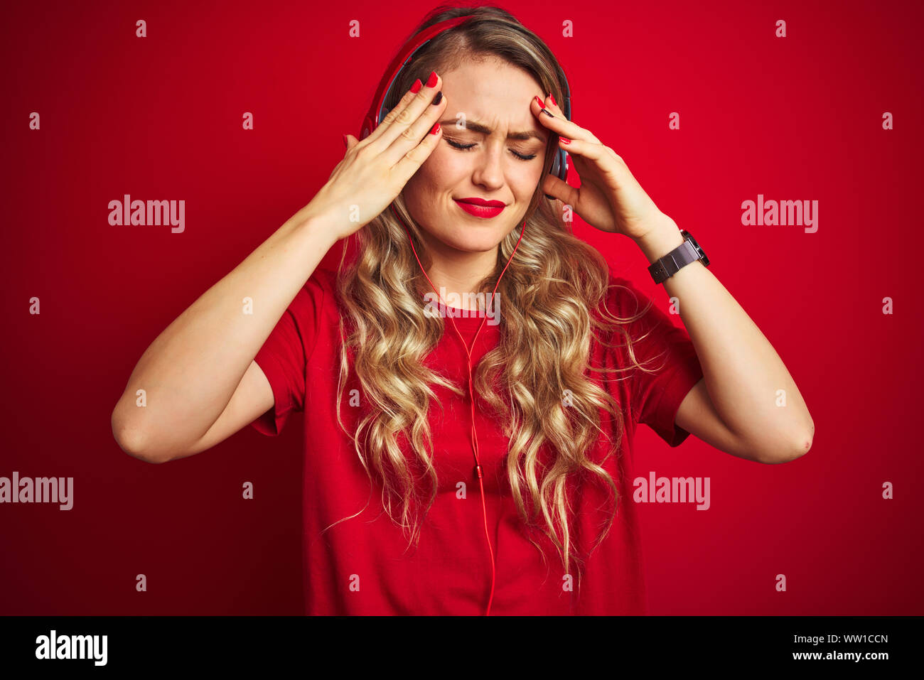Young beautiful woman wearing headphones over red isolated background
