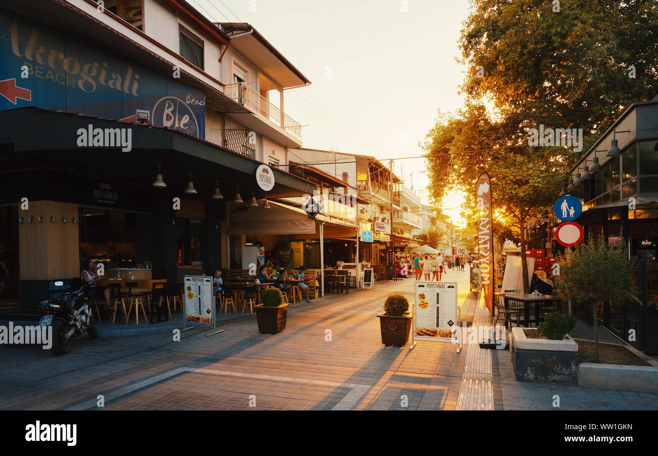 Stavros, Greece - August 29, 2019: The main street of the town full of shops and restaurants during summer season at sunset. Stock Photo