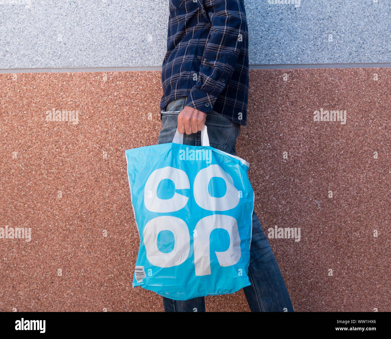 Man carrying Coop supermarket plastic shopping bag. UK Stock Photo