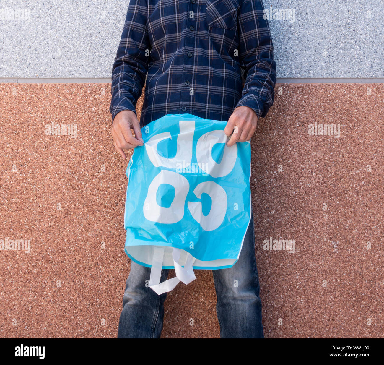 Man holding empty Coop supermarket plastic shopping bag. UK Stock Photo